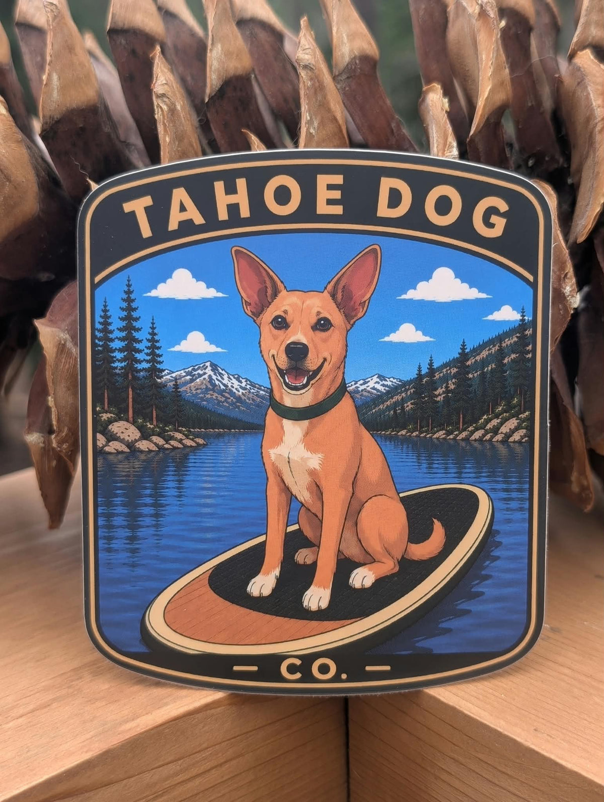 Wylie tan Chihuahua Tahoe Dog sticker paddleboarding on Donner Lake with Sierra Nevada mountains and pine trees in the background